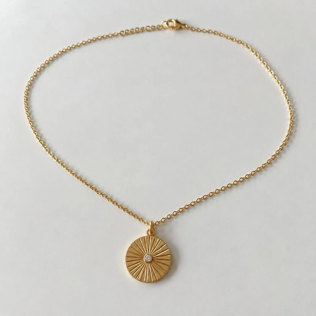 Gold medallion necklace lying on a light surface, photographed from above