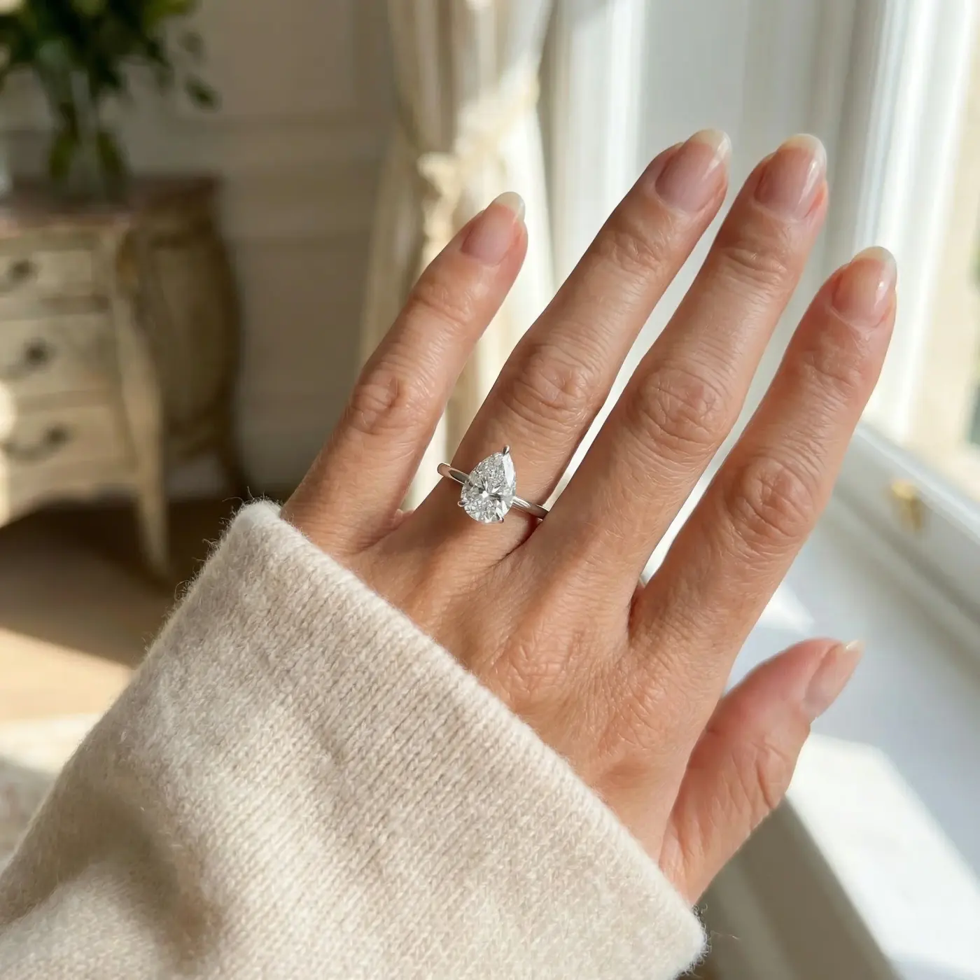 Jewelry lifestyle image: pear cut engagement ring hand